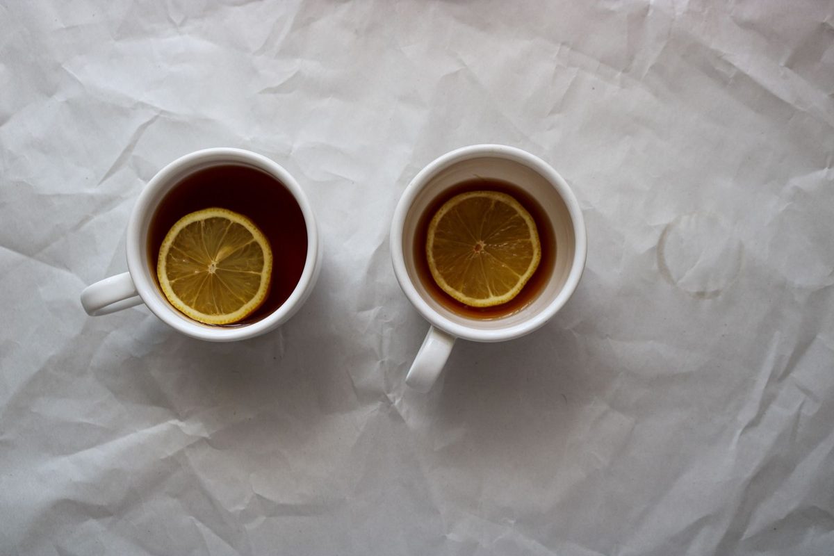Dos tazas de té con rodaja de limón sobre papel blanco