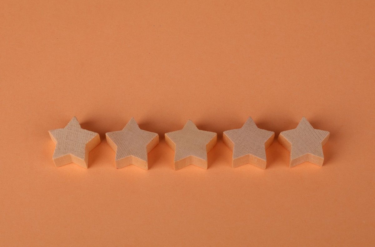 Cinco estrellas de madera en fila sobre un fondo naranja