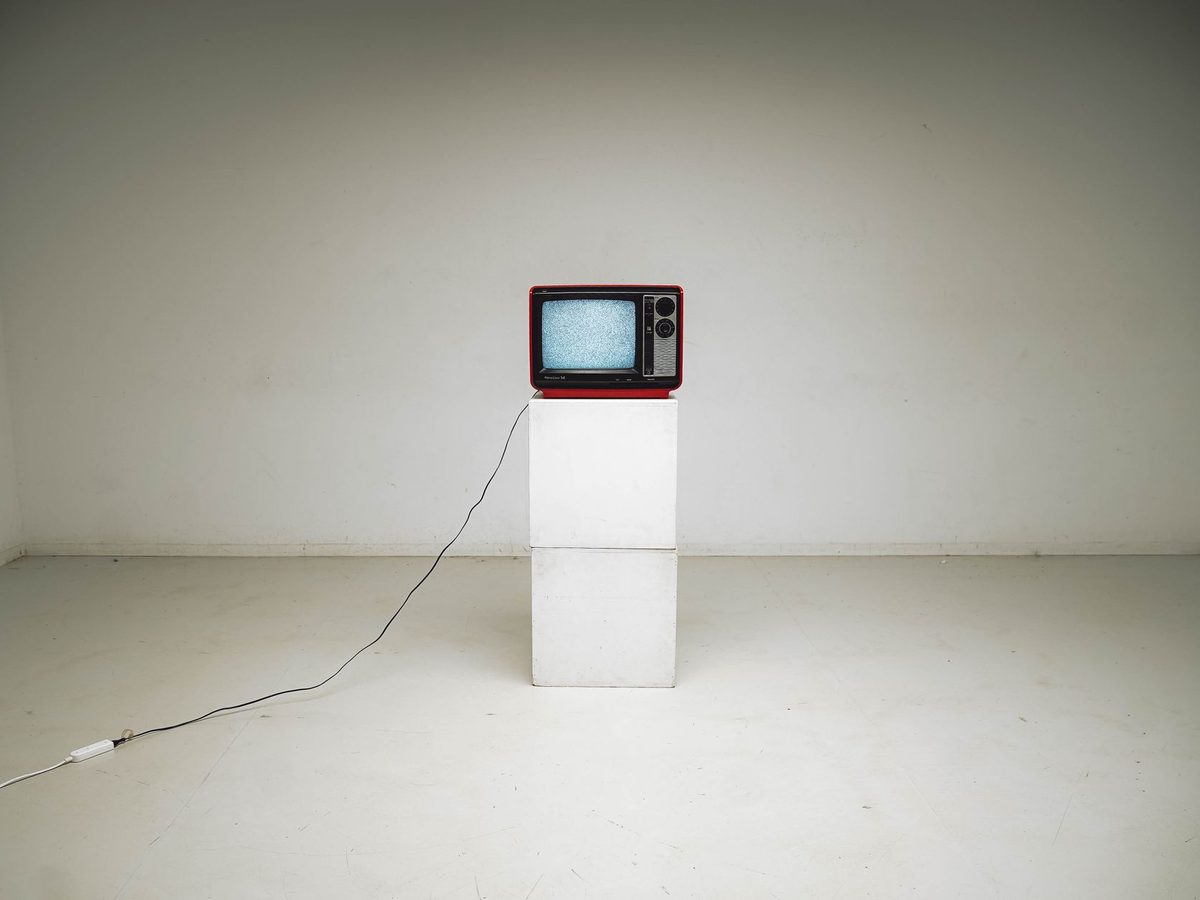 Un televisor antiguo sobre un pedestal en una sala blanca