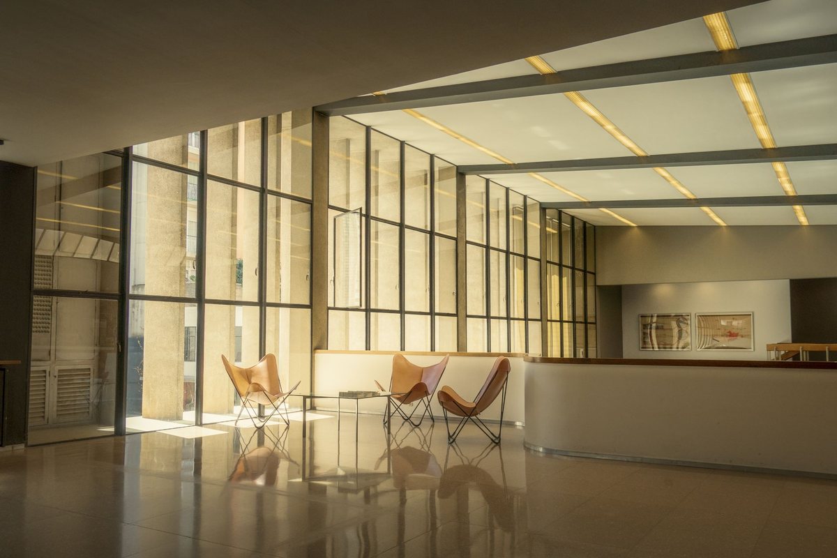 Vestíbulo moderno y luminoso de un edificio, con sillones de cuero vacíos