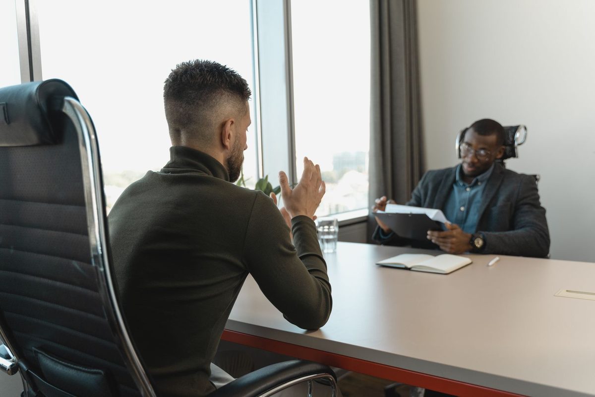 Dos hombres en una entrevista de trabajo en una oficina con ventanales