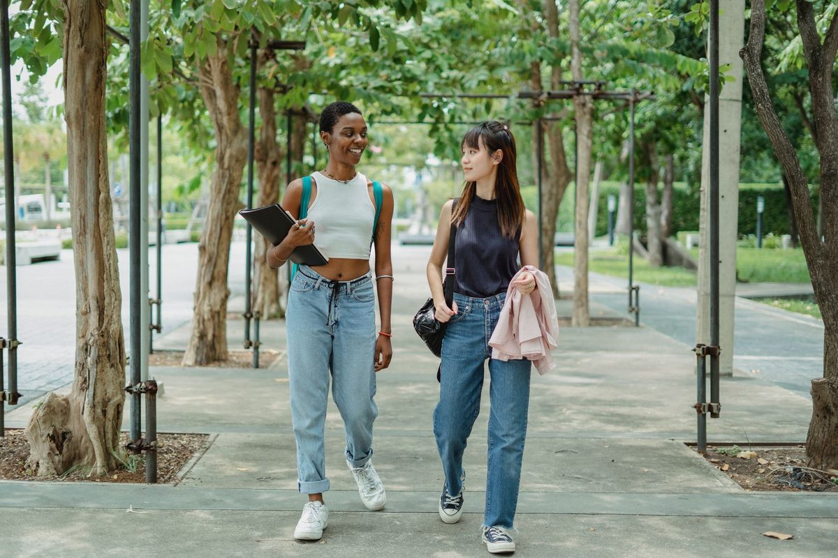 Dos amigas paseando y charlando por un paseo arbolado un día luminoso