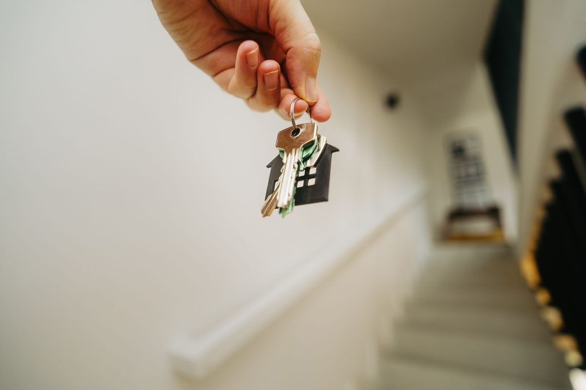 Mano que sostiene unas llaves con llavero en forma de casa
