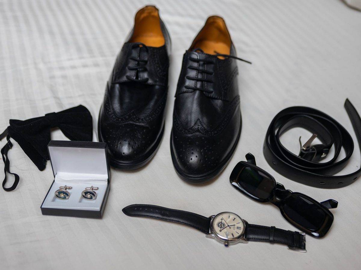 Una pajarita, unos zapatos y un reloj sobre una cama