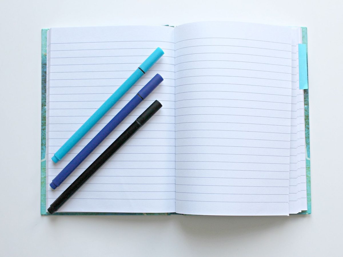 Un cuaderno abierto con tres bolígrafos encima