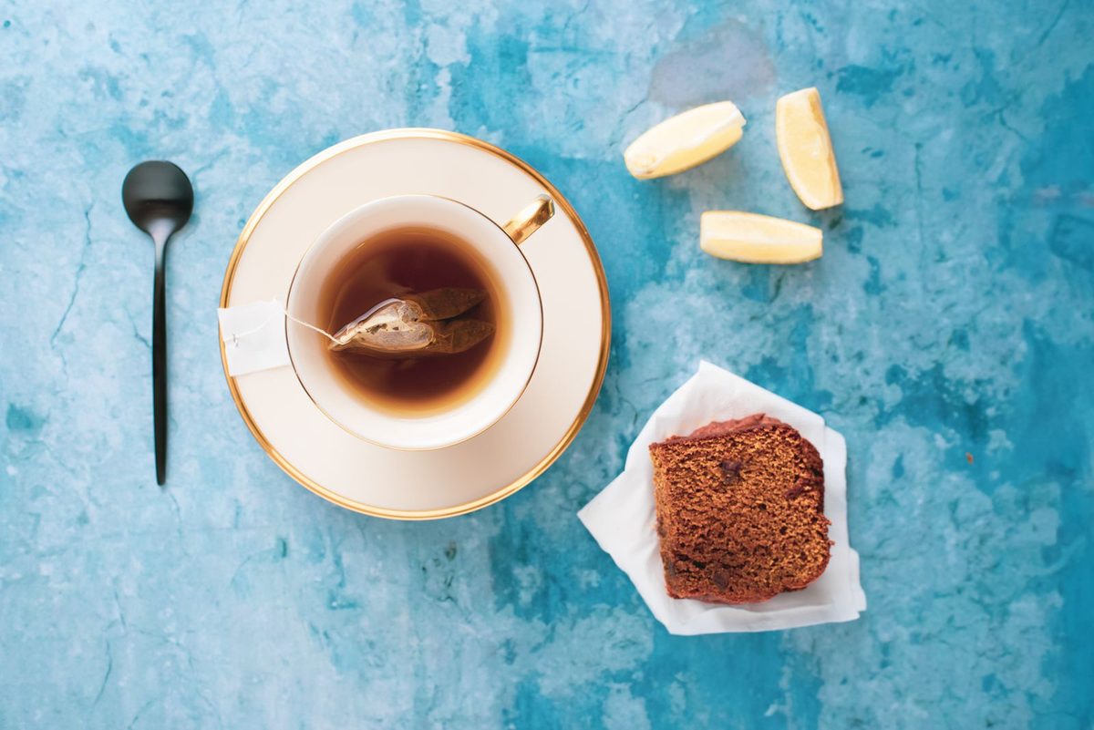 Taza de té con un trozo de bizcocho y rodajas de limón