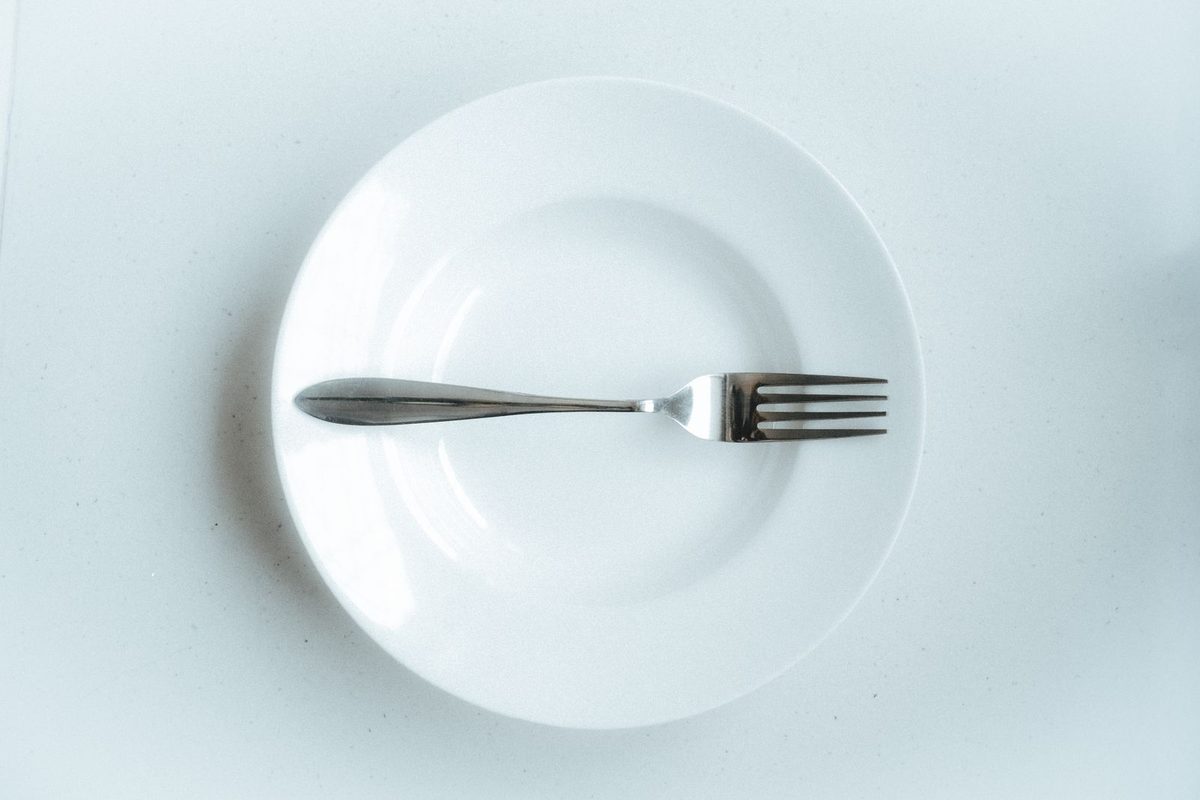 Plato blanco vacío con un tenedor tras terminar de comer