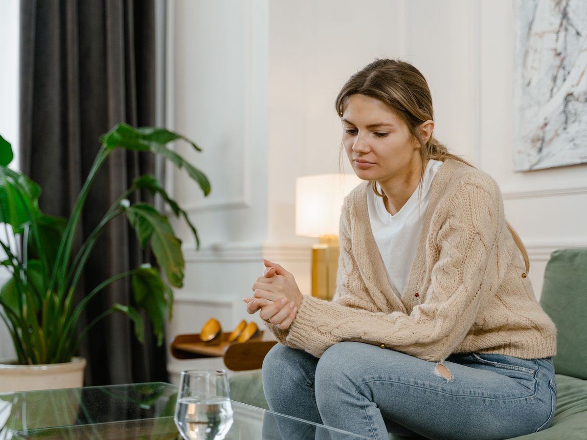 Una mujer sentada en un sofá, pensativa