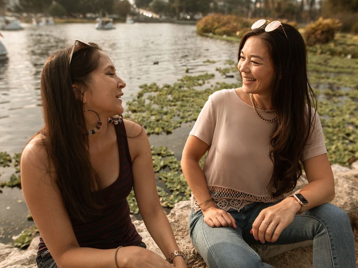 Dos mujeres charlan sentadas junto a un lago